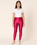 Person wearing shiny pink leggings and a white t-shirt on a beige background