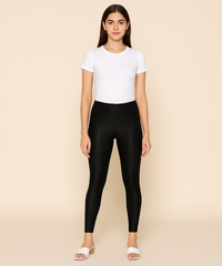 Woman wearing a white t-shirt and black leggings on a beige background
