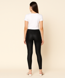 Person wearing black leggings and a white top on a beige background