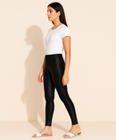 Woman wearing black leggings and a white t-shirt on a beige background