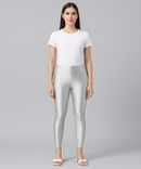 Woman wearing silver leggings and a white t-shirt on a gray background