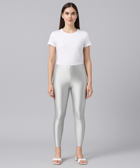 Woman wearing silver leggings and a white t-shirt on a gray background
