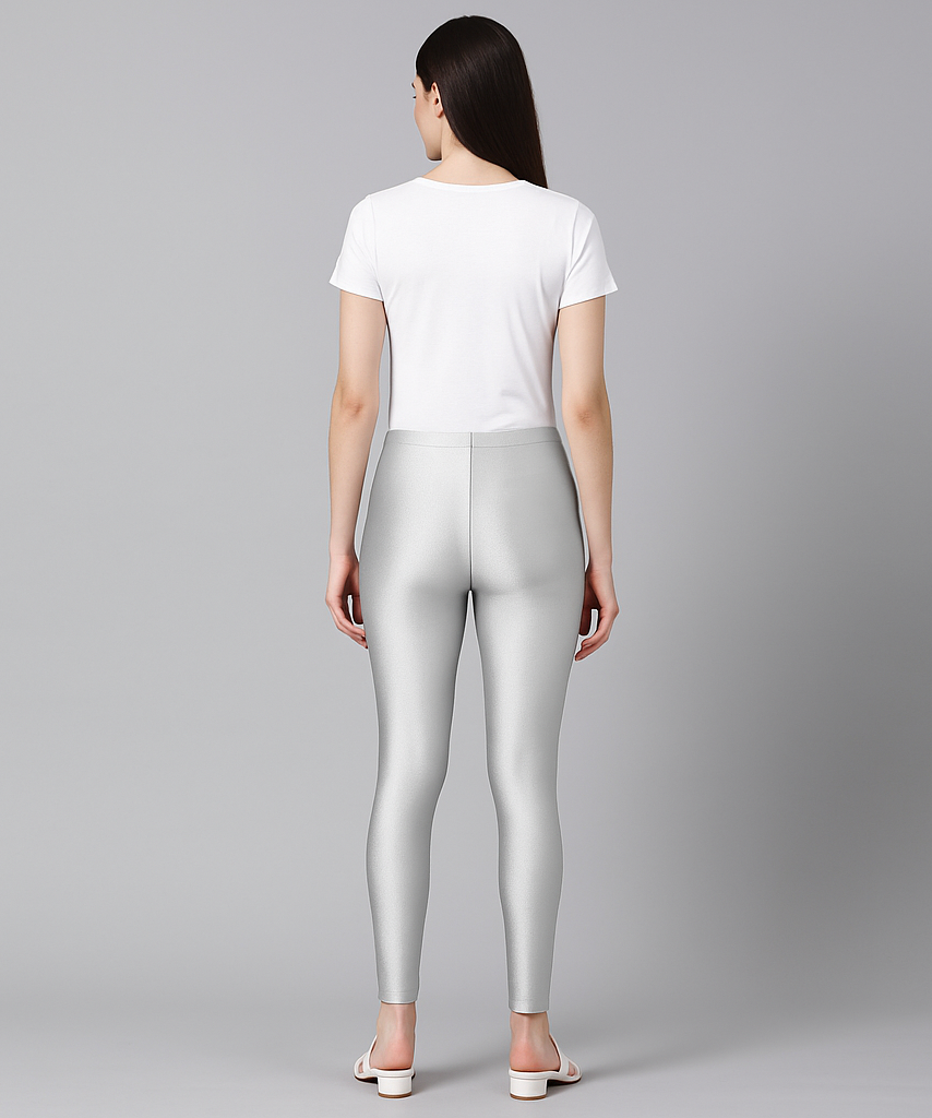 Woman wearing silver leggings and a white t-shirt on a gray background