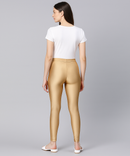 Woman wearing gold leggings and a white t-shirt on a gray background