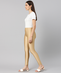 Woman wearing beige leggings and a white top on a gray background