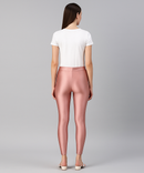 Woman wearing pink leggings and a white top on a gray background