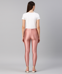 Woman wearing pink leggings and a white top on a gray background