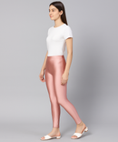 Woman wearing a white top and pink leggings on a gray background